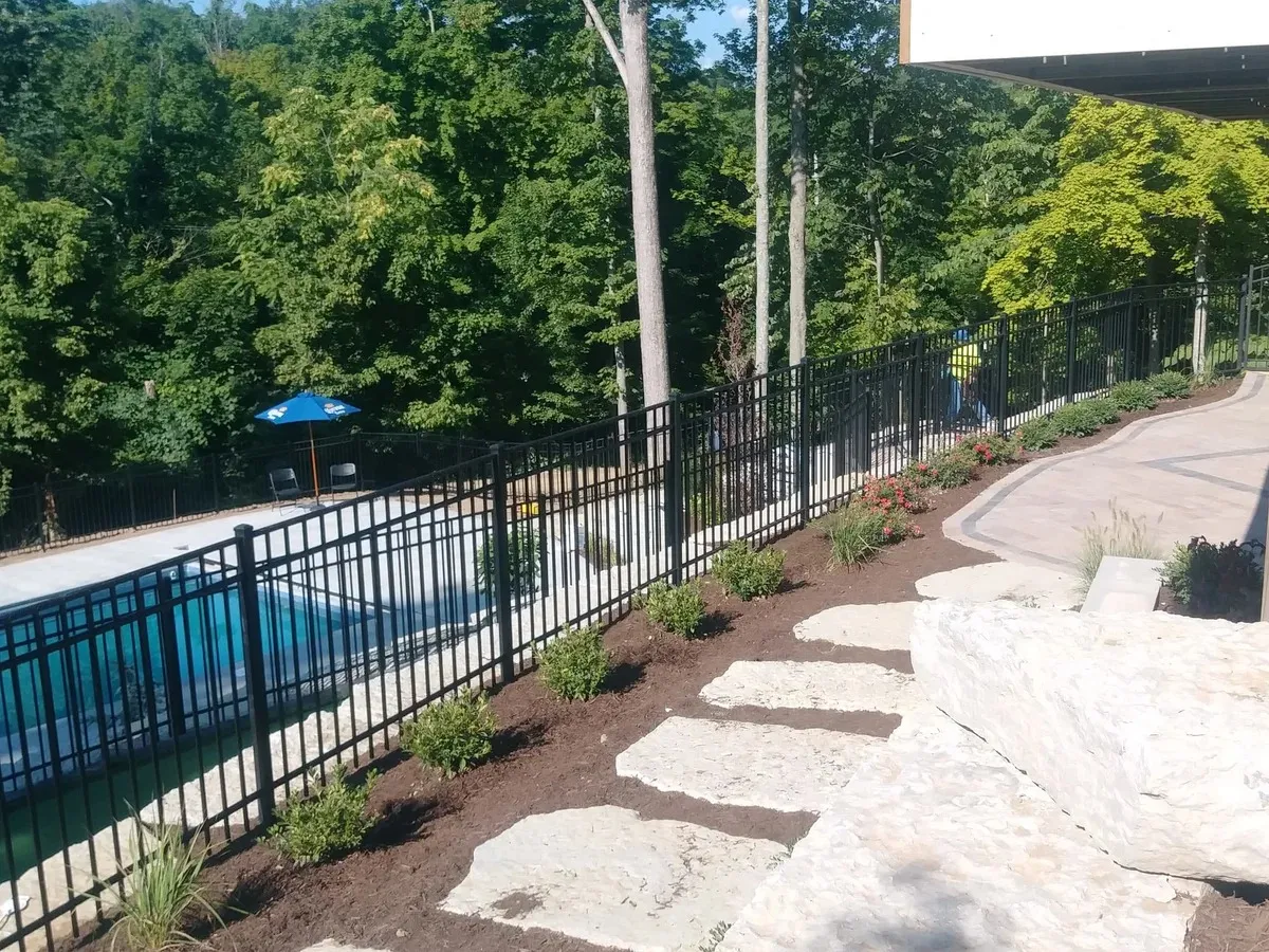 Black ornamental aluminum fence installed along a residential driveway